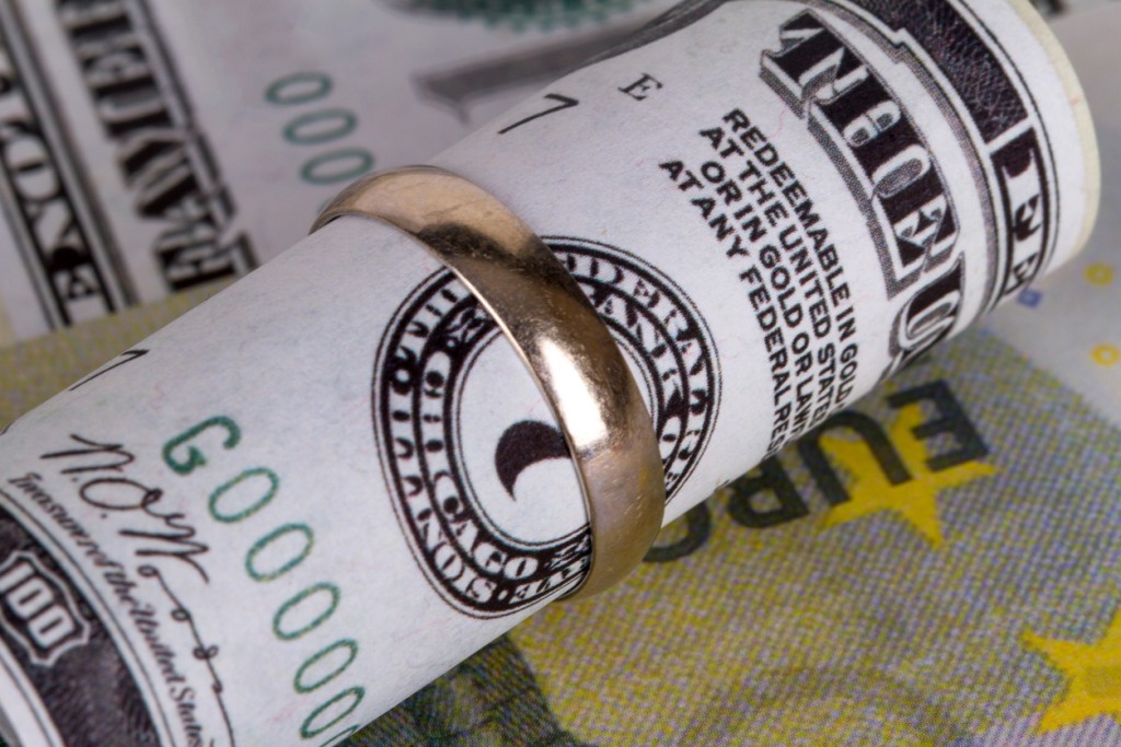 Dollar and euro banknotes with marriage ring in finance and marriage expenses concept.